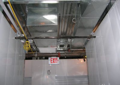 Commercial building ceiling with exposed ductwork, yellow cable with light cover, and an illuminated exit sign—reminiscent of residential HVAC design.