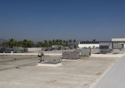 Rooftop in Orange County with multiple HVAC units and palm trees in the background under a clear CA sky.