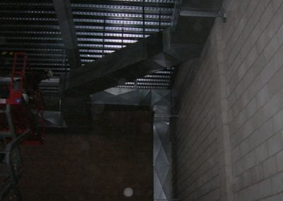 Overhead view of metal ductwork installed along a brick wall and ceiling of an industrial or commercial building, showcasing the precision typical of residential HVAC systems found in Orange County, CA.