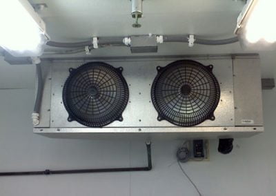 Ceiling-mounted industrial cooling fans inside a white room with exposed wiring and lighting fixtures installed by a CA HVAC contractor.