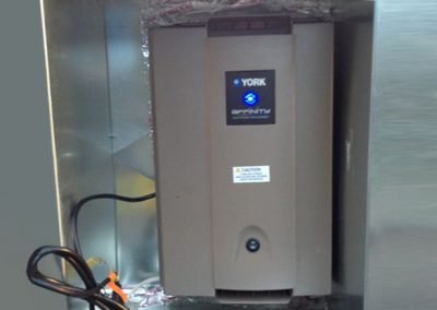 A York Affinity dehumidifier, combined with air conditioning, is installed inside a metal enclosure with a power cord visible on the left side. Ideal for homes in Orange County, CA.